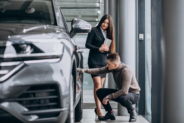 Junger Mann mit Verkäuferin in einem Autohaus