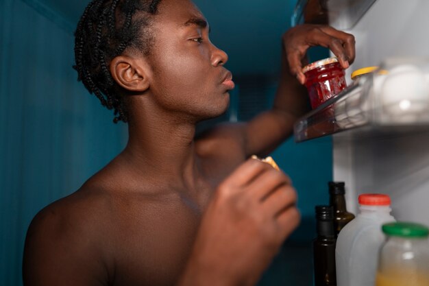 Junger Mann öffnet den Kühlschrank zu Hause für einen Snack mitten in der Nacht