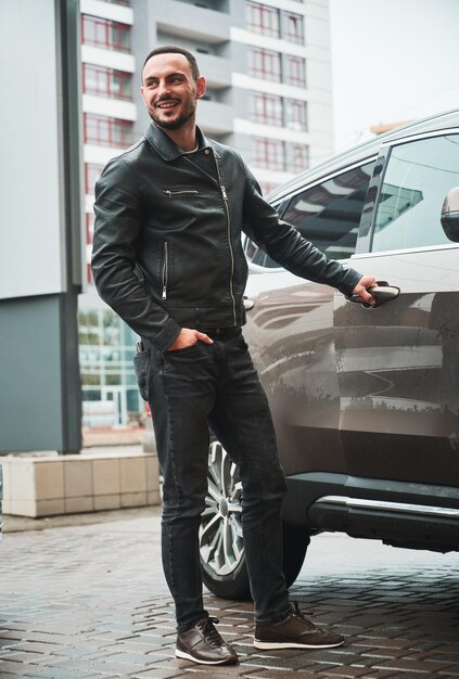Junger Mann posiert in der Nähe seines modernen Autos