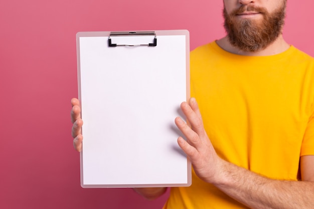 Kostenloses Foto junger mann schaut aus den augen weiße leere leere plakatwand für werbeinhalt isolierte studioaufnahme