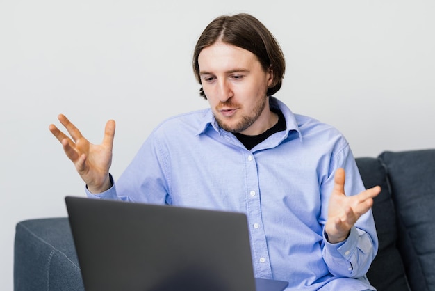 Junger mann sitzt auf sofa und macht videoanruf auf laptop zu hause