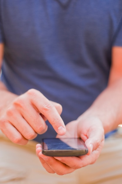 Junger Mann sitzt im Park und Texting eine Nachricht