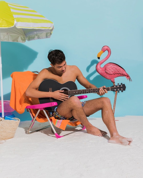 Kostenloses Foto junger mann spielt gitarre am strand