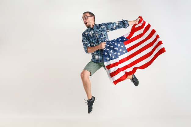 Junger Mann springt mit Flagge der Vereinigten Staaten von Amerika lokalisiert auf weißem Studio.