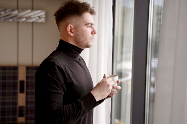 Junger Mann trinkt Kaffee in einem Hotelzimmer