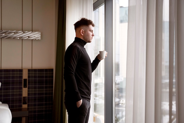Junger Mann trinkt Kaffee in einem Hotelzimmer