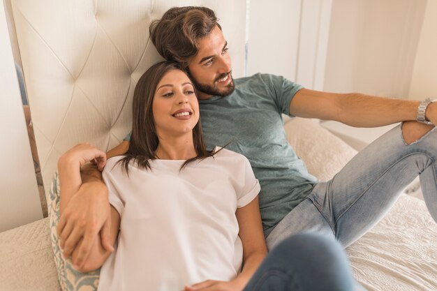 Junger Mann und Frau, die auf Bett sich entspannt