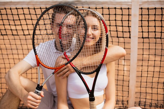 Junger Mann und Frau mit Tennisschlägern