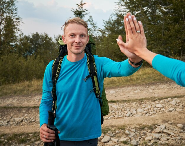 Junger Mann wandert im Freien und gibt seiner Frau fünf