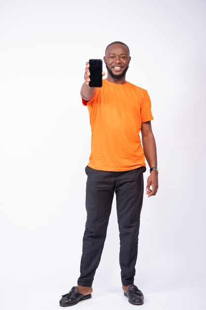 Junger Mann zeigt seinen Telefonbildschirm isoliert auf weißem Hintergrund