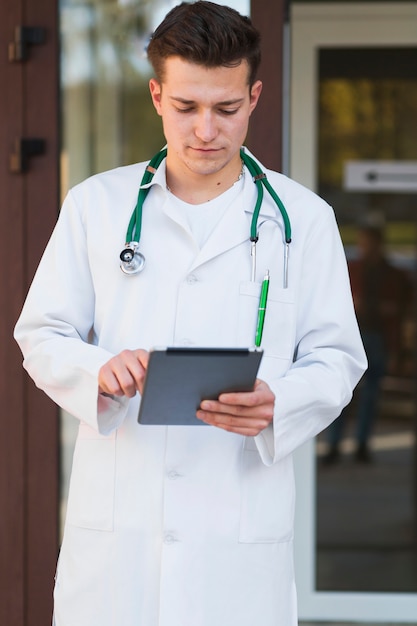 Kostenloses Foto junger mediziner mit tablette am krankenhauseingang