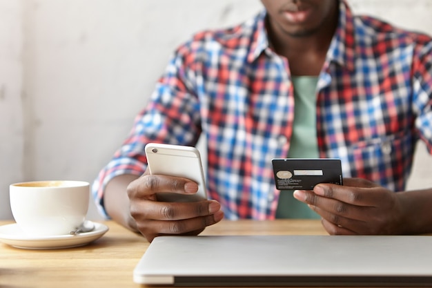 Kostenloses Foto junger modischer kerl, der an einem café mit smartphone sitzt