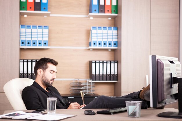 Junger müder Geschäftsmann, der in seinem Büro arbeitet. Kaufmann im beruflichen Umfeld