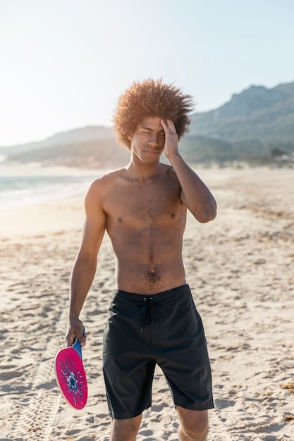 Kostenloses Foto junger müder schwarzer mann, der auf strand steht