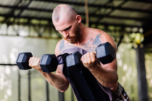 Junger muskulöser tätowierter starker Muskelbärtiger europäischer Mann, der harte Übung tut