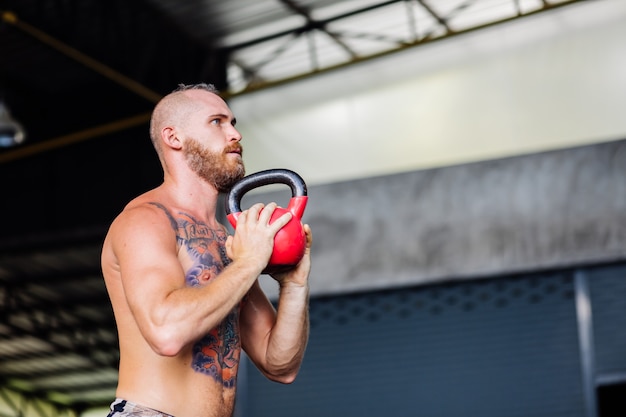 Junger muskulöser tätowierter starker Muskelbärtiger europäischer Mann, der harte Übung tut