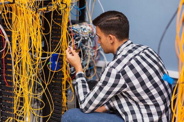 Junger Netzingenieur, der mit Drähten arbeitet