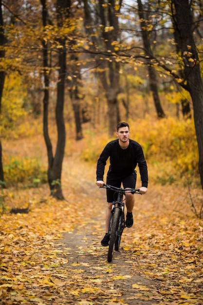 Junger passender Mann während einer Radtour an einem sonnigen Tag im Herbstpark