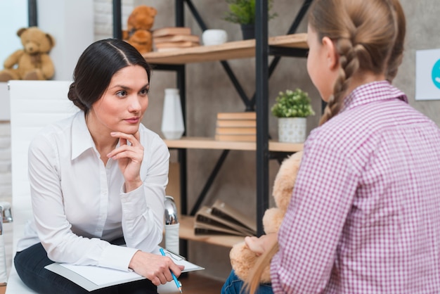 Junger Psychologe, kleines Mädchen beobachtend, das vor ihr sitzt