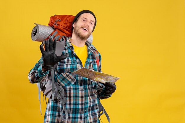 junger Rucksacktourist mit schwarzem Hut, der eine Karte hält, die High Five gibt