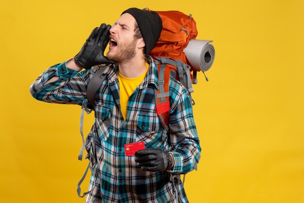 junger Rucksacktourist mit schwarzem Hut, der eine Kreditkarte hält, die jemanden anruft?