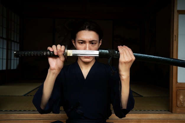 Junger Samurai, der Vorderansicht der Klinge hält