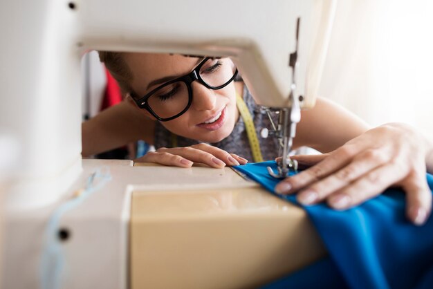 Junger Schneider, der mit Nähmaschine arbeitet