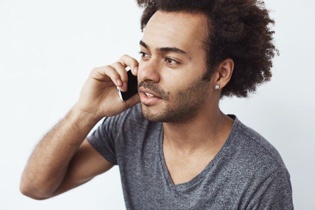 Junger schöner afrikanischer Mann, der am Telefon spricht.
