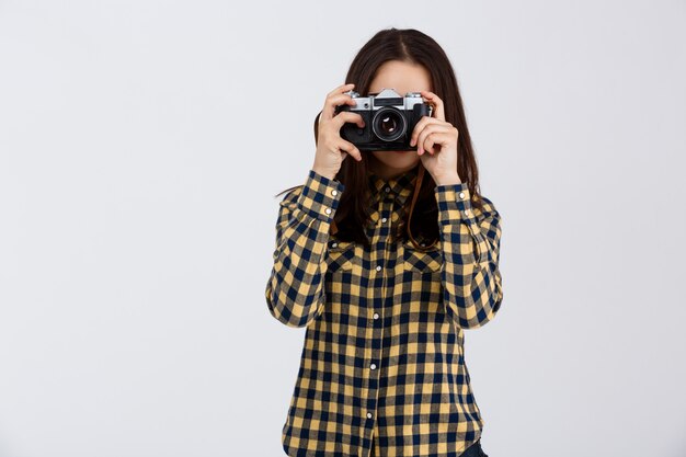 Junger schöner brünetter Fotograf über weißer Wand.