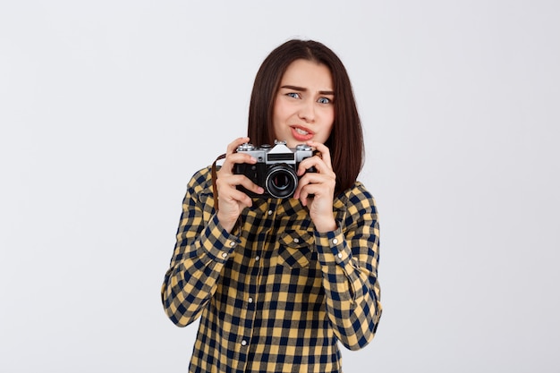 Junger schöner brünetter Fotograf über weißer Wand.