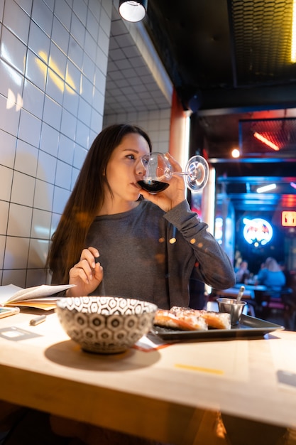 Junger schöner Brunette trinkt Wein in einem Café