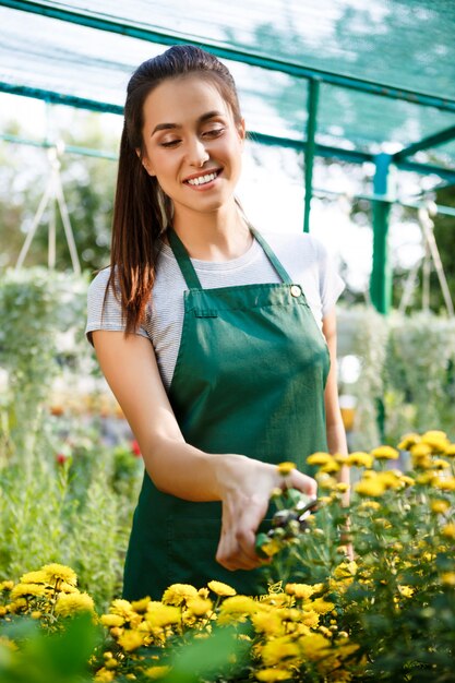 Junger schöner Florist, der Blumen über Blury kümmert.