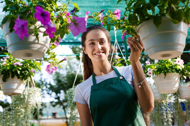 Junger schöner Florist, der unter Blumen lächelt.