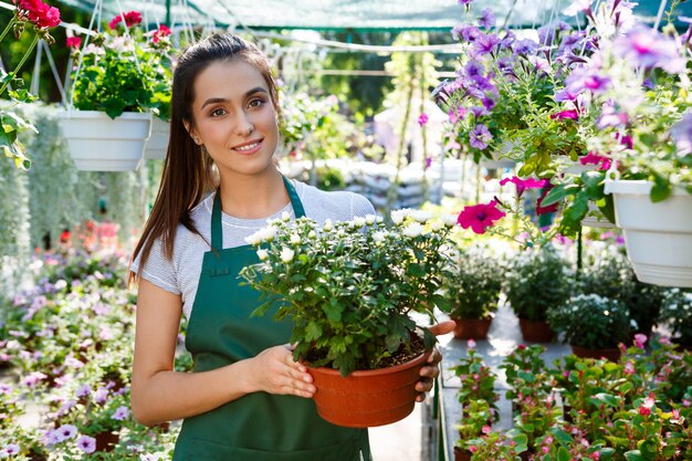 Junger schöner Florist, der unter Blumen lächelt.