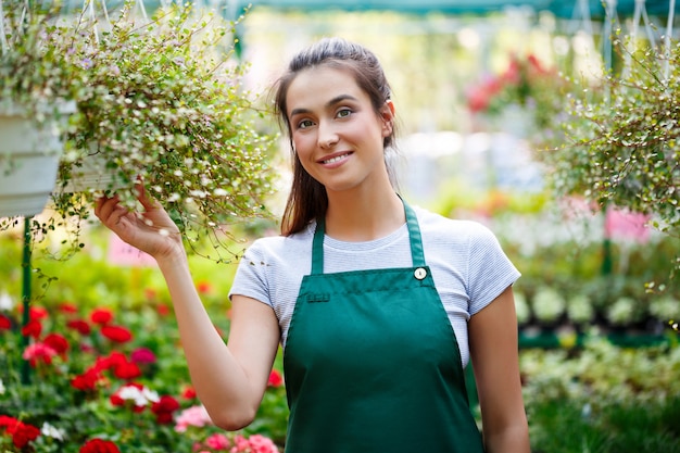 Junger schöner Florist, der unter Blumen lächelt.