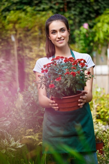 Junger schöner Florist, der unter Blumen lächelt.