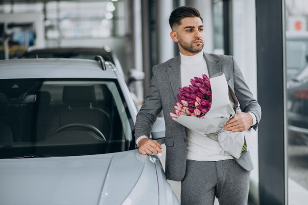 Junger schöner Geschäftsmann, der Blumenstrauß der schönen Blumen liefert