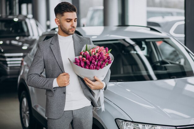 Junger schöner Geschäftsmann, der Blumenstrauß der schönen Blumen liefert