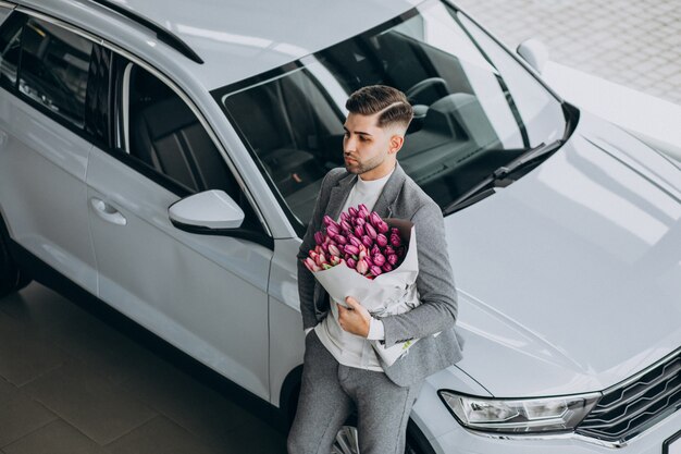 Junger schöner Geschäftsmann, der Blumenstrauß der schönen Blumen liefert