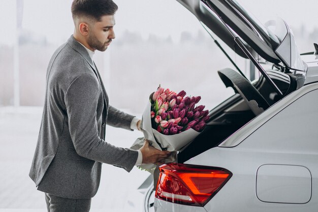 Junger schöner Geschäftsmann, der Blumenstrauß der schönen Blumen liefert