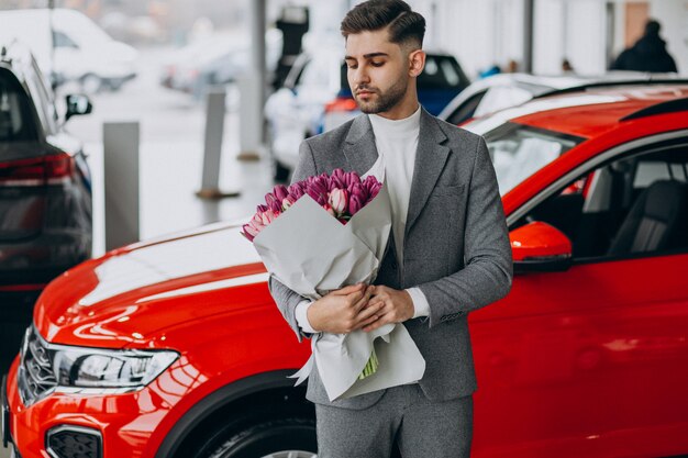 Junger schöner Geschäftsmann, der Blumenstrauß der schönen Blumen liefert