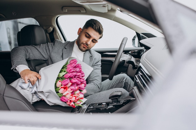 Junger schöner Geschäftsmann, der Blumenstrauß der schönen Blumen liefert