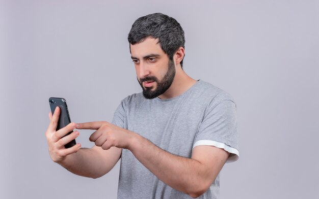 Junger schöner kaukasischer Mann, der sein Handy lokalisiert auf weißem Hintergrund mit Kopienraum verwendet