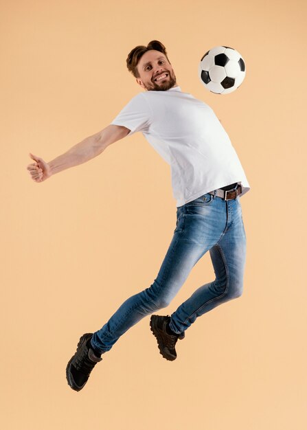 Junger schöner Mann, der mit Fußballball springt