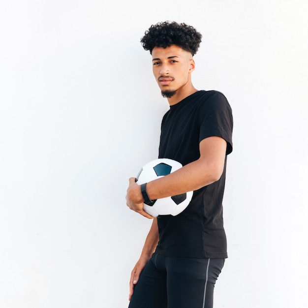 Kostenloses Foto junger schwarzer mann, der fußball zum körper drückt