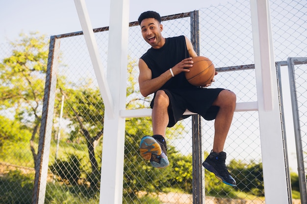 Junger schwarzer Mann, der Sport treibt, Basketball spielt, aktiven Lebensstil, Sommermorgen, lächelnd glücklich, Spaß zu haben