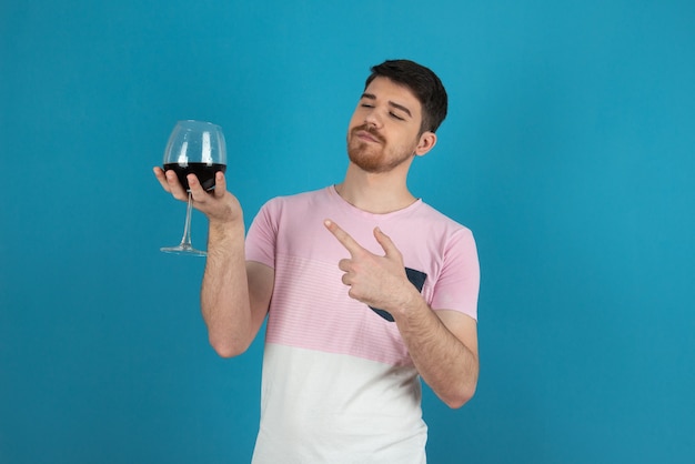 Junger selbstbewusster, gutaussehender kerl, der mit dem finger auf ein glas wein zeigt.