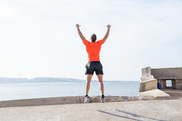 Junger sportlicher Mann, der draußen im Sommer springt