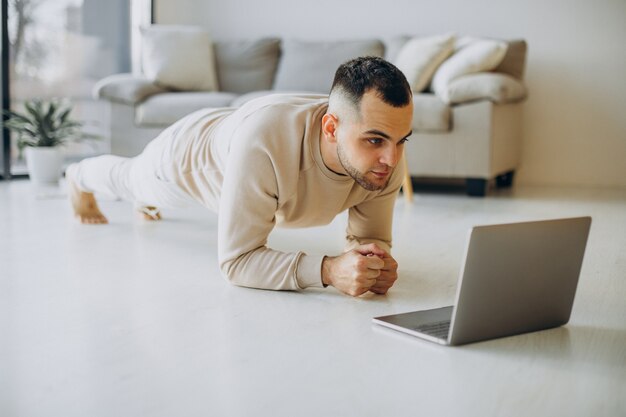 Junger sportlicher Mann, der zu Hause Yoga praktiziert