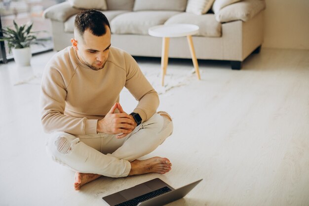 Junger sportlicher Mann, der zu Hause Yoga praktiziert